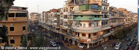 Busy street corner among residential buildings with signs, cars and motorcycles passing by