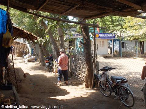 Man in hat walking dirt path with bicycles and wooden houses