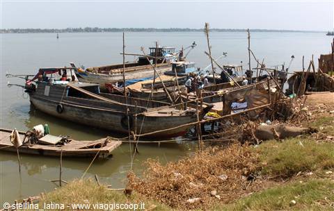 Wooden boats moored along the muddy riverbank