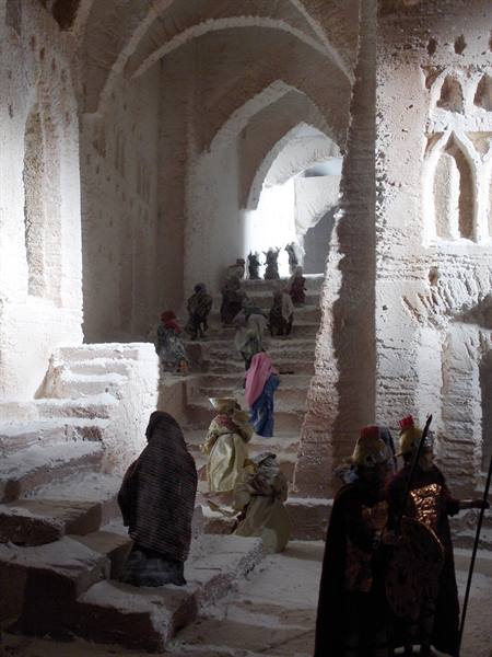 Costumed figures on rock stairways among carved arches in stone