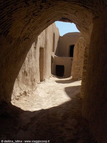 Mud-brick alley beneath an arch, ancient earthen houses