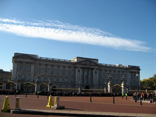 Crowd gathered before the stone facade of Buckingham Palace