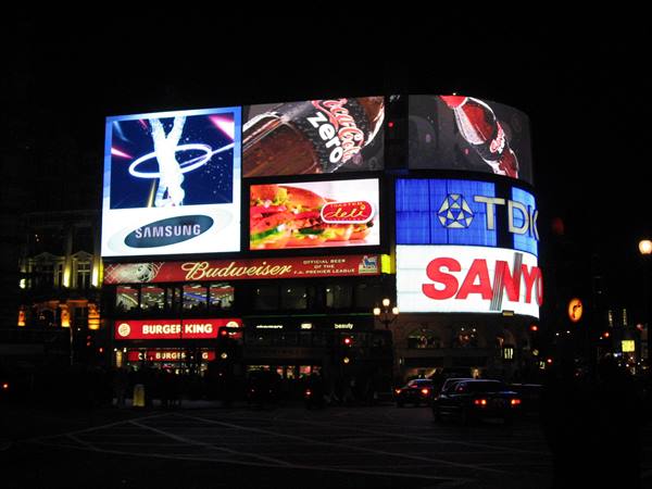 Piccadilly Circus at night: bright Samsung, Coca-Cola, TDK, Sanyo billboards above traffic