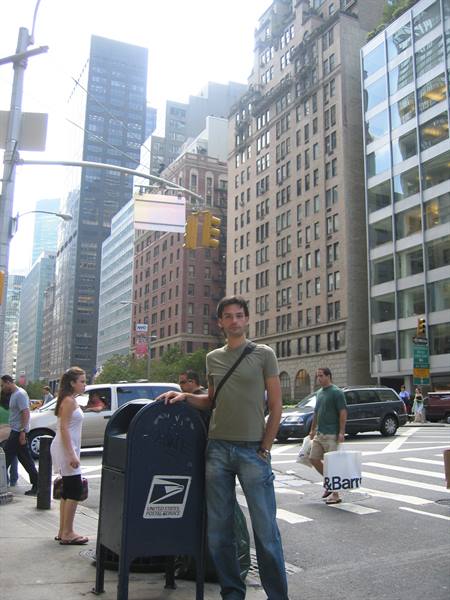 Man leaning on a USPS mailbox on a Manhattan sidewalk