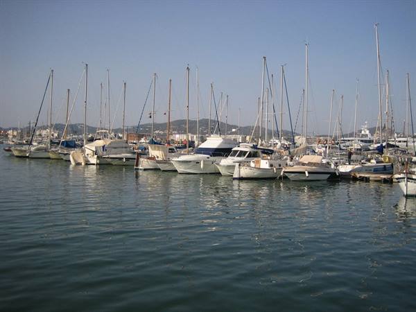 Sailboats and yachts moored at the marina, masts against the blue sky