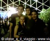 Four friends smiling at night under an illuminated lattice canopy