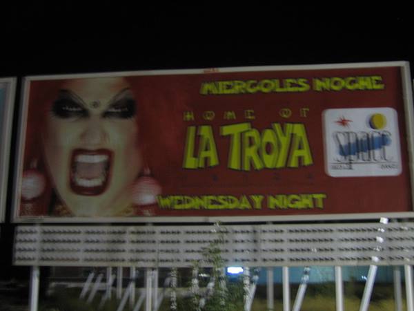 Night billboard in red with screaming face, La Troya sign