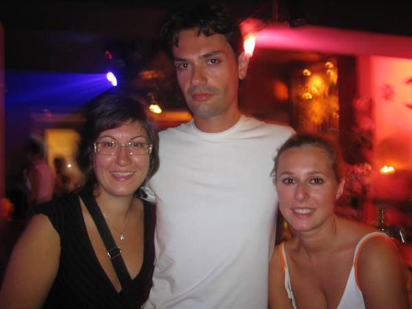 Three friends posing and smiling in a nightclub lit by red and blue lights