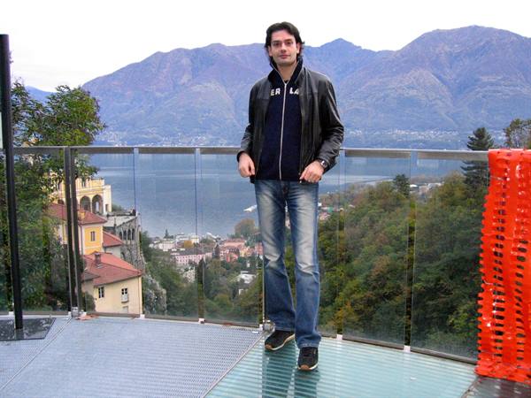 Man in leather jacket on glass terrace above the Madonna del Sasso sanctuary