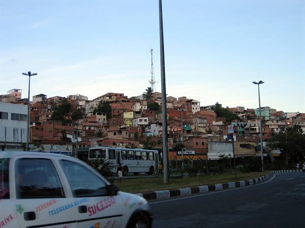 Car and bus on road before brick house hillside favela, Belo Horizonte