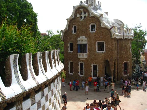 Tourists by the stone lodge with wavy mosaic roof at Park Güell, Barcelona