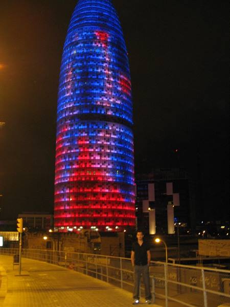 Tourist in front of the Torre Agbar lit in blue and red, Barcelona
