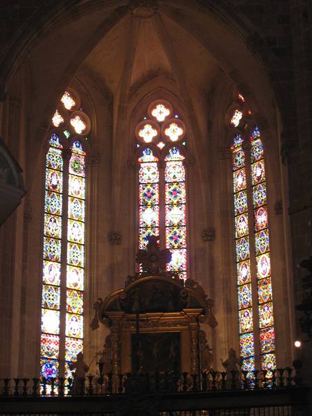 Gothic apse with bright polychrome stained glass above a gilded altar