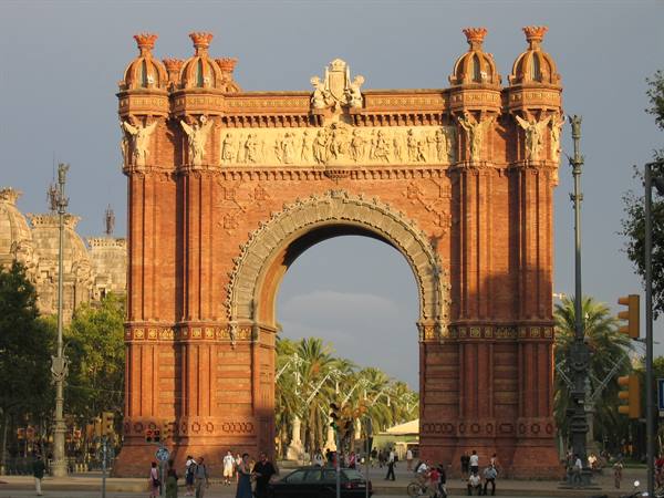 Barcelona's Arc de Triomf, red brick arch with traffic and pedestrians in afternoon light