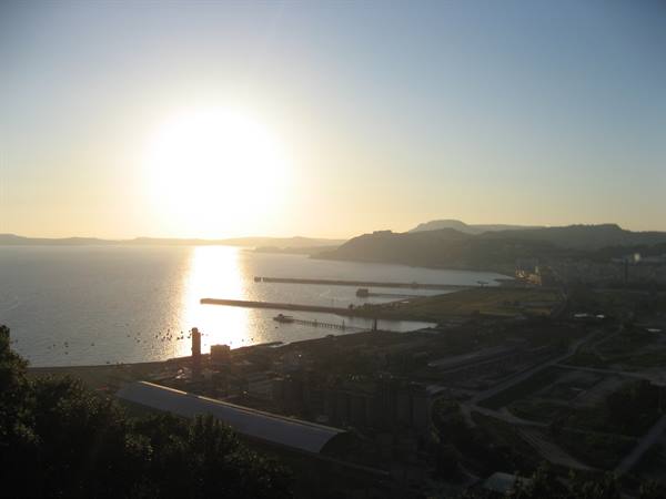 Low sun over the sea, concrete harbor piers and hill silhouettes above Salerno