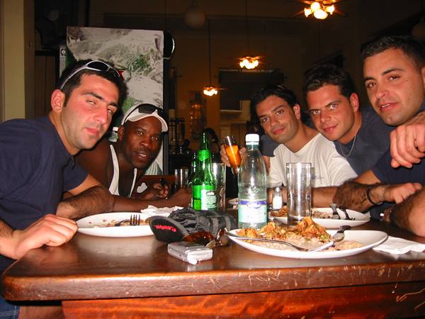 Five friends at a restaurant table, empty plates, bottles and warm light