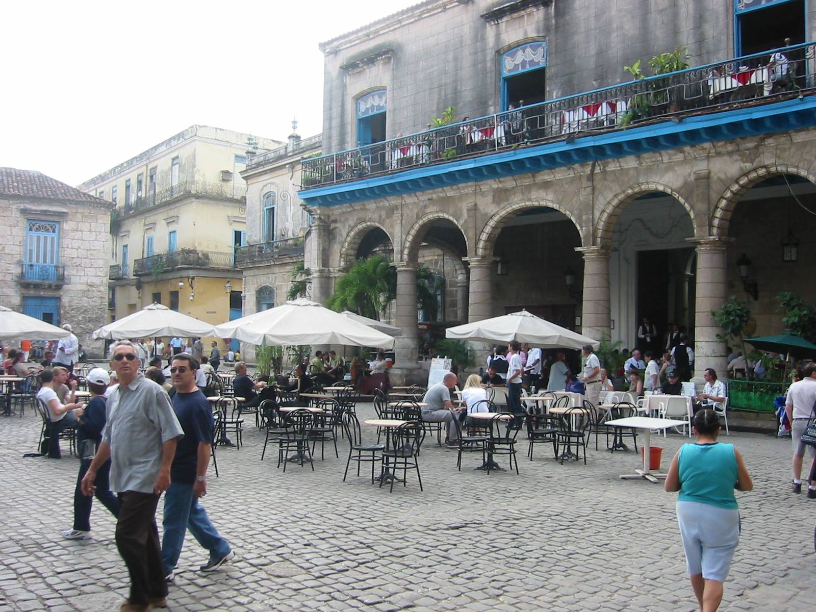 People at cafe tables under umbrellas in Plaza Vieja, Havana