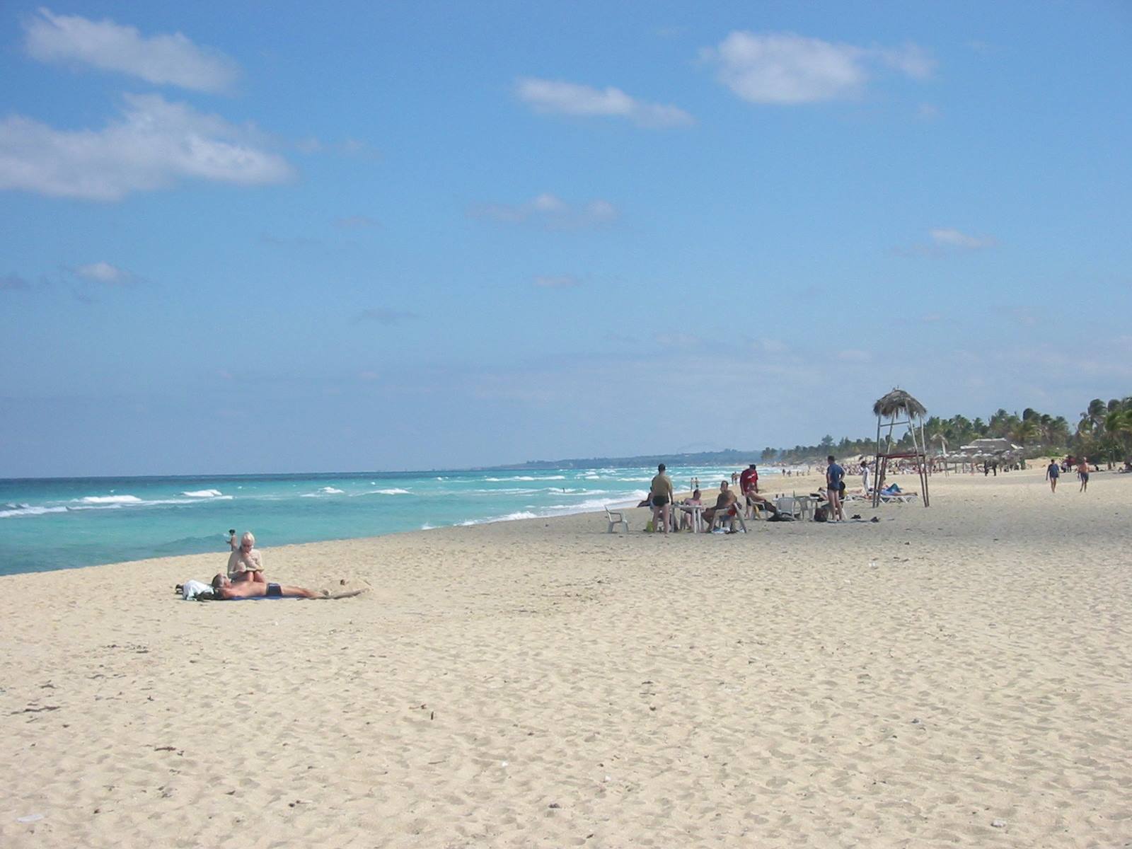 Tourists lounging on white sand at Varadero, thatched umbrellas and turquoise sea