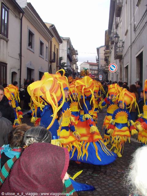 Carnival parade with yellow and blue flame costumes among the crowd on a sloped street