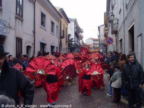 Red ladybug carnival costumes parading through a crowded small-town street