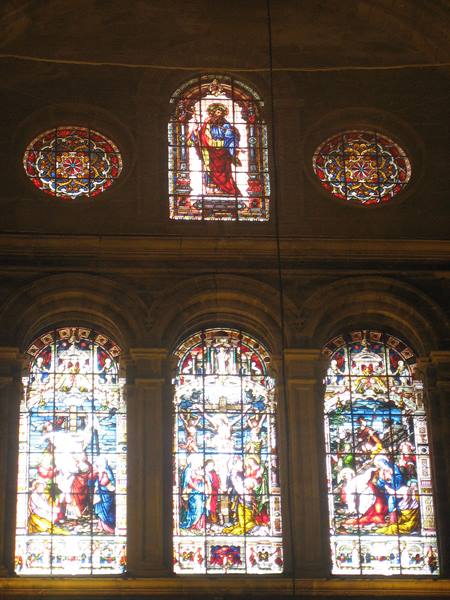 Colorful stained glass windows with biblical scenes glowing in a church