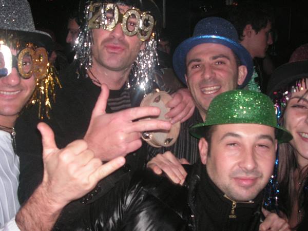 Friends in glitter hats and 2009 glasses celebrate New Year's at a club