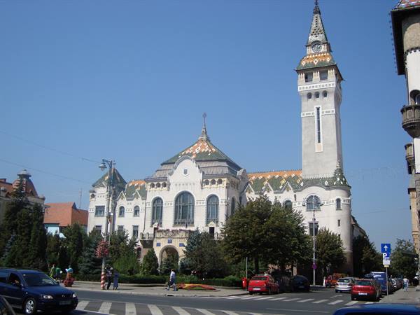 Subotica City Hall, white Art Nouveau building with tiled clock tower, traffic and pedestrians