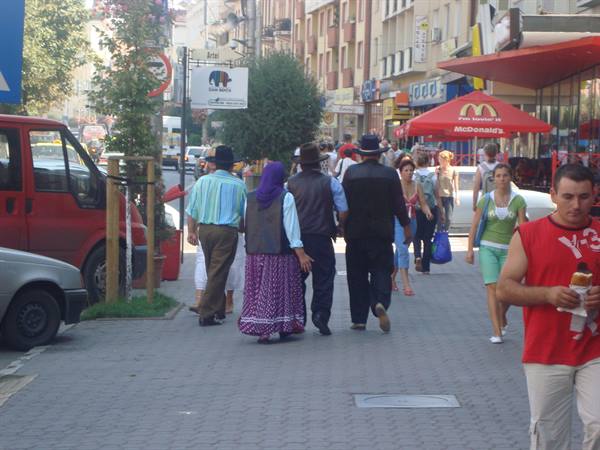 People in traditional clothing walk down a busy pedestrian street