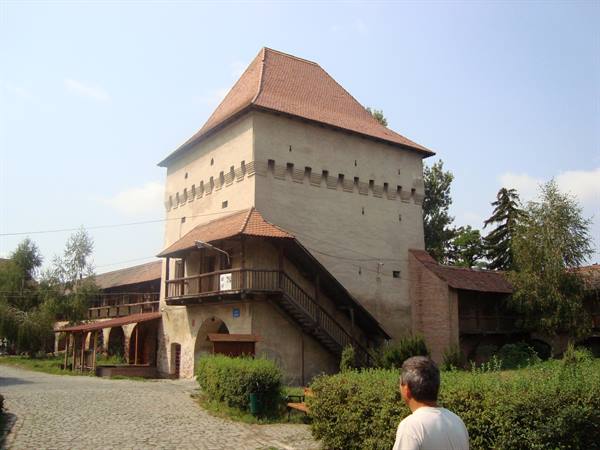 Tourist before a medieval plastered tower with red tile roof and wooden balcony
