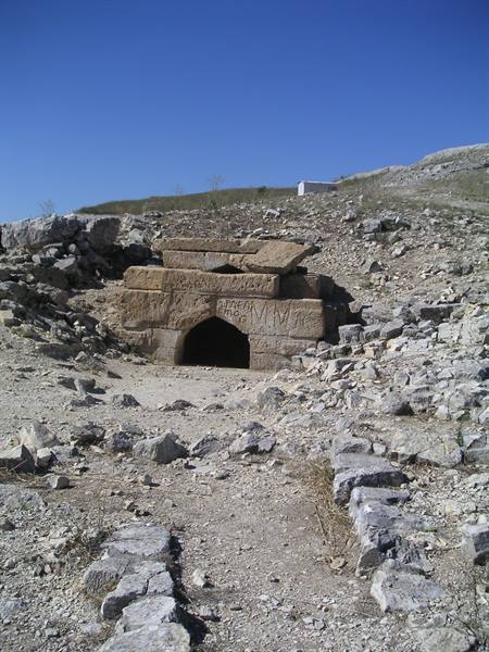 Ancient stone doorway among hewn blocks and rubble under blue sky