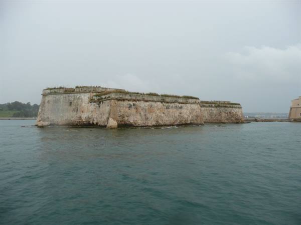 Old stone sea fortress with thick walls under a grey sky