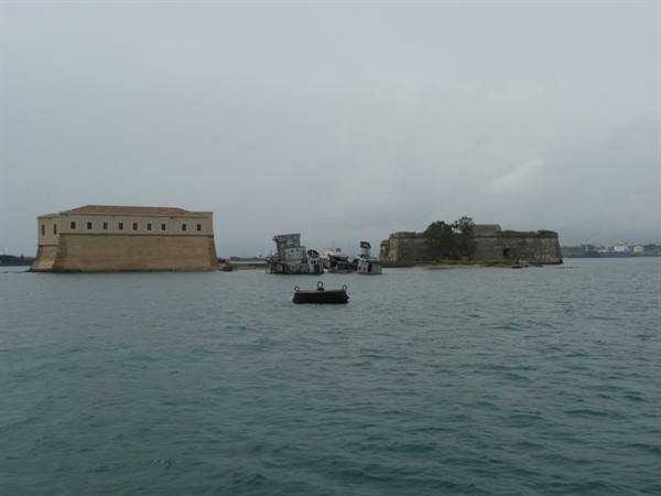 Old fortresses on islets in Corfu harbour, grey sky and choppy sea