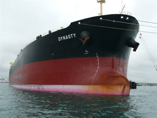 The cargo ship Dynasty, black and red hull, moored in harbor under gray sky