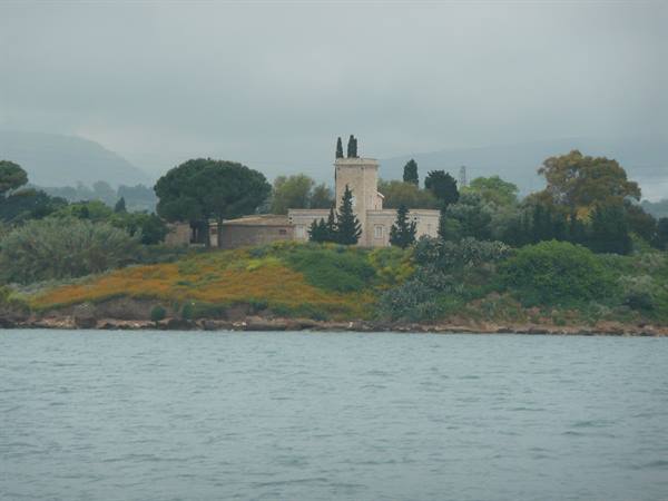Stone villa with tower among pines and Mediterranean scrub, seen from the sea