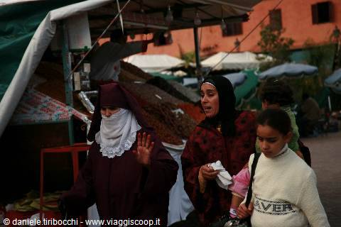 Veiled women walk past spice stalls in the Marrakech market