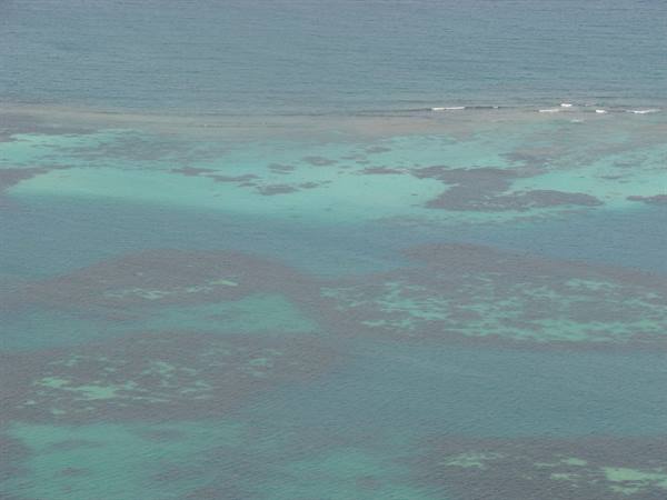 Turquoise water with visible coral reef and small breaking waves