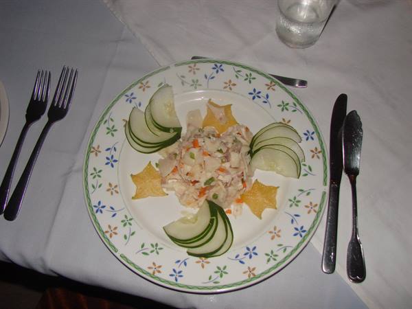 Fish salad plate with cucumber slices and star-shaped chips on white tablecloth
