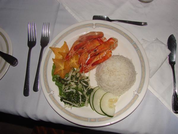 Plate with prawns, white rice, salad and cucumber on tablecloth