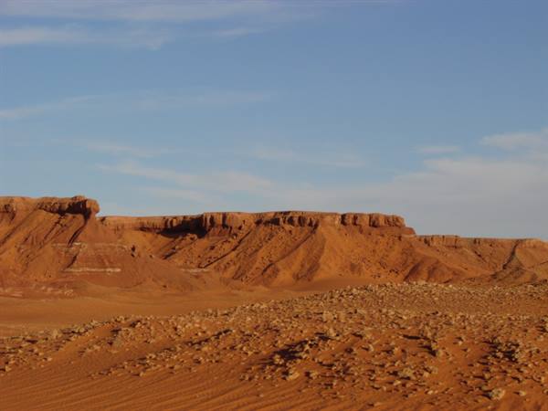 Eroded red rock cliff in the desert under a blue sky