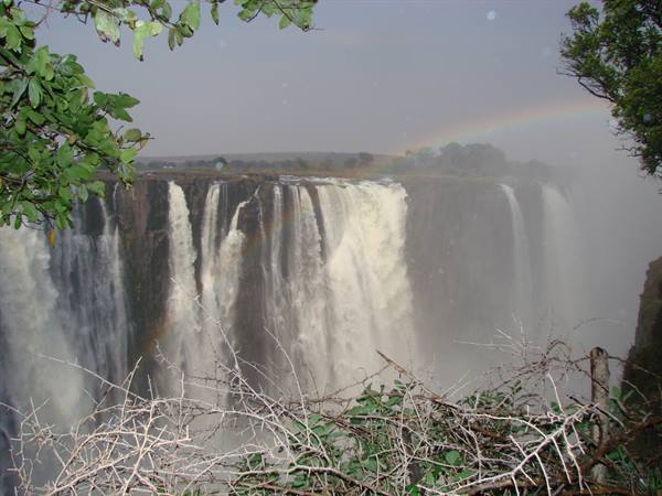 Victoria Falls, white water plunges into mist with a rainbow