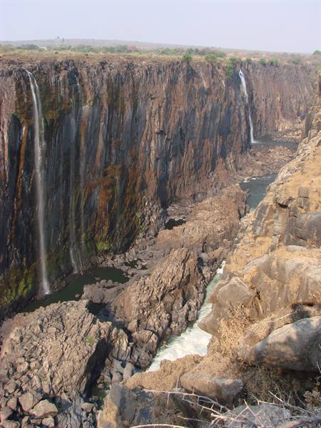 Thin waterfalls over dark basalt cliffs, rapids flowing between boulders in the gorge