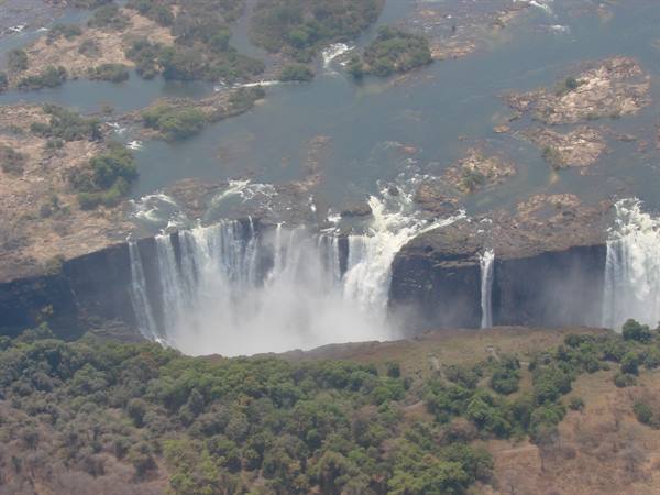 Victoria Falls seen from above, Zambezi water plunges into the gorge amid mist and greenery