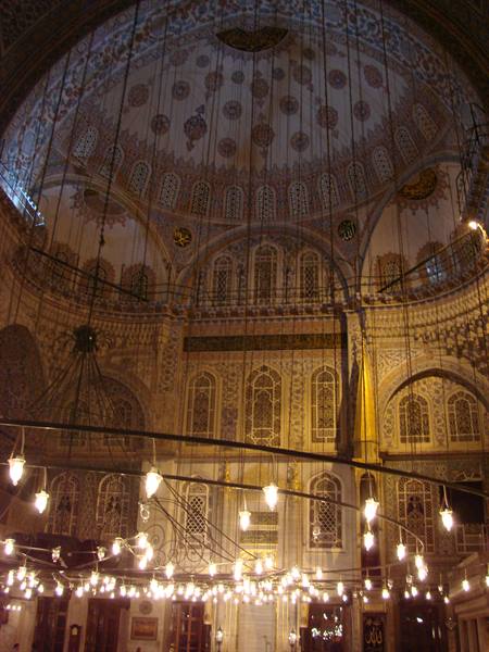 Inside Istanbul's Blue Mosque, decorated dome and glowing lamps
