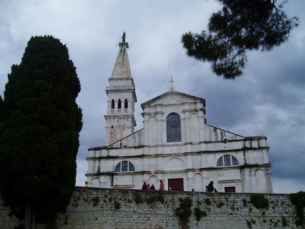 Visitors walk past the Church of St. Euphemia in Rovinj under cloudy skies