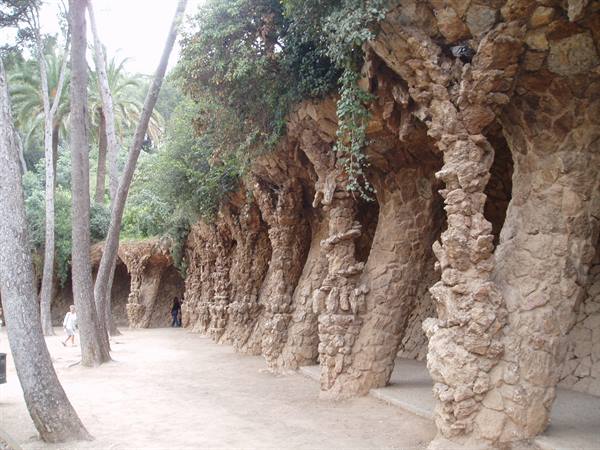 Sloping rough stone colonnade at Park Güell, with palm trees and soft daylight