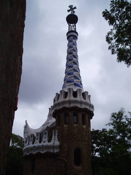 Stone tower with white and blue mosaic spire at Parc Güell