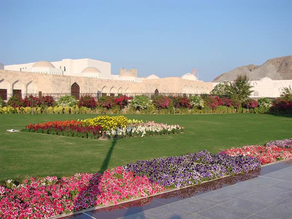 Colorful flowerbeds and green lawn before white domed walls