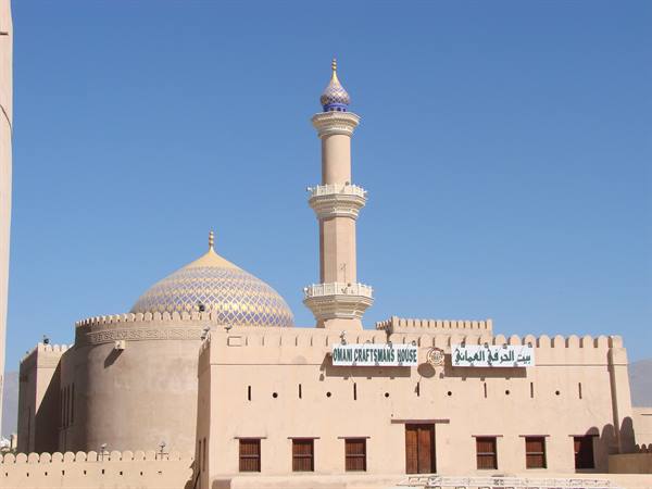 Minaret and tiled dome above the Omani Craftsman's House in Nizwa, blue sky