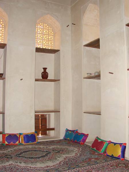 Plastered niches with shelves and vase, colorful cushions on carpet, lattice light