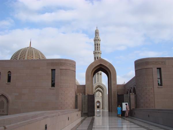 Sultan Qaboos Grand Mosque in Muscat: minaret and dome amid sandstone arches